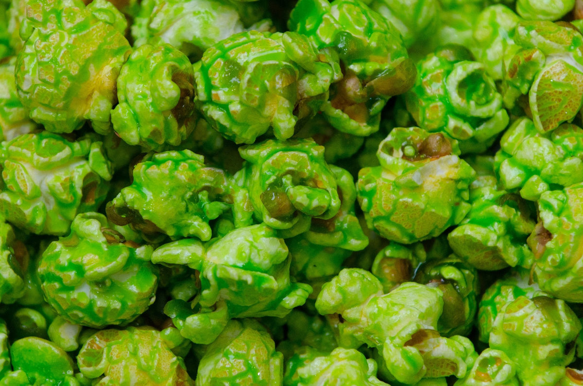 Close-up of bright green, green apple popcorn coated with a glossy green glaze, filling the entire frame.